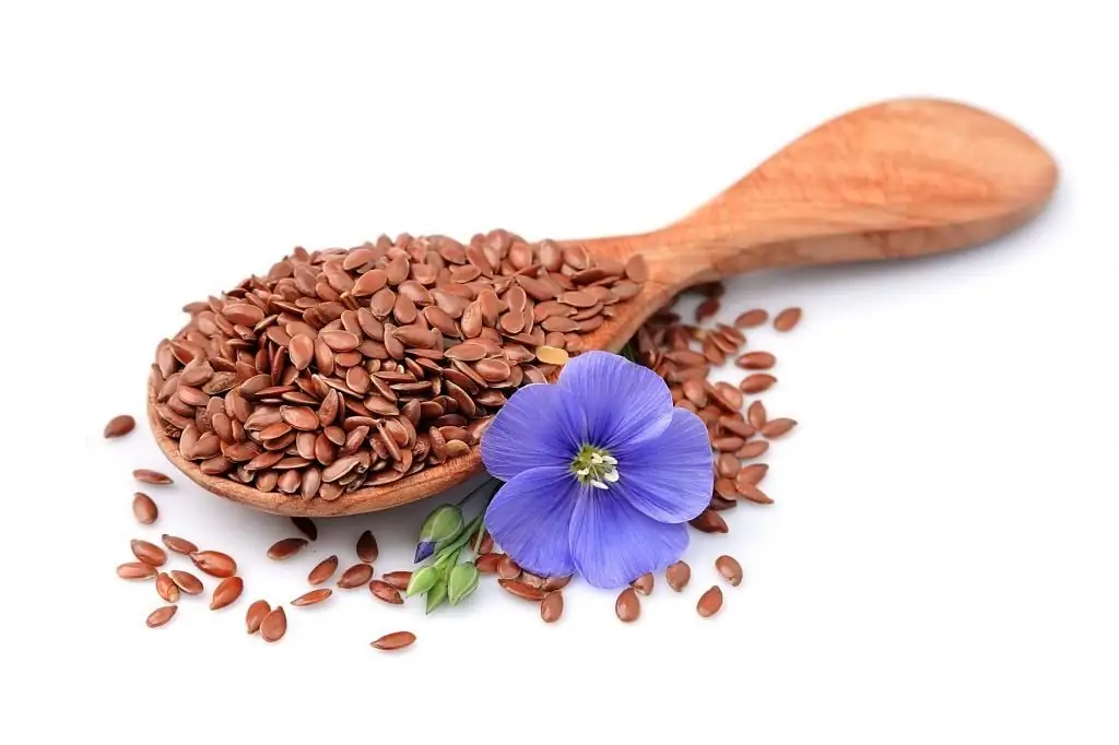 flax seeds in a spoon and a blue flower